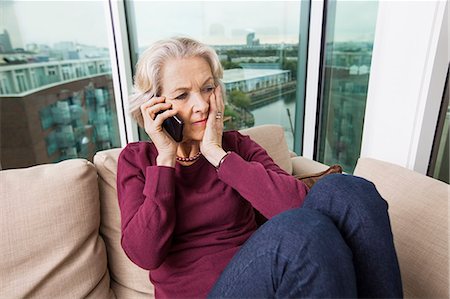 phone worried person - Worried senior woman answering smart phone on sofa at home Stock Photo - Premium Royalty-Free, Code: 693-07456440