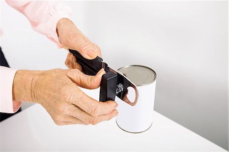 Cropped image of senior businesswoman opening canned food at office Stock Photo - Premium Royalty-Free, Code: 693-07456481