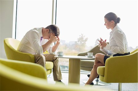 sitting sad lady side view - Businesspeople in serious discussion at office lobby Stock Photo - Premium Royalty-Free, Code: 693-07542160