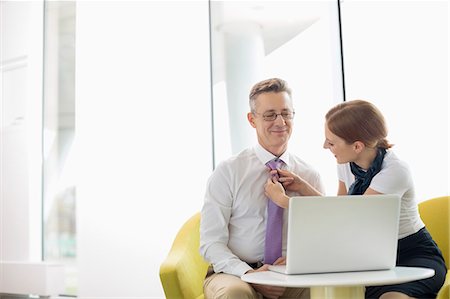 simsearch:693-03301293,k - Businesswoman putting on tie to male colleague at lobby Stock Photo - Premium Royalty-Free, Code: 693-07542172