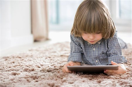 Boy using digital tablet while lying on rug at home Stockbilder - Premium RF Lizenzfrei, Bildnummer: 693-07542214