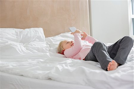 simsearch:693-06120706,k - Full length of happy girl using smart phone in bed Stock Photo - Premium Royalty-Free, Code: 693-07542221
