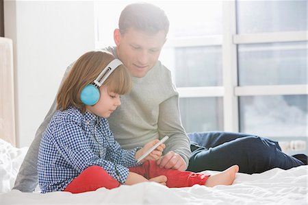 father son indoors - Father with boy listening music on headphones in bedroom Photographie de stock - Premium Libres de Droits, Code: 693-07542222