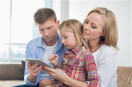 Parents with daughter using digital tablet at home Fotografie stock - Premium Royalty-Free, Codice: 693-07542234