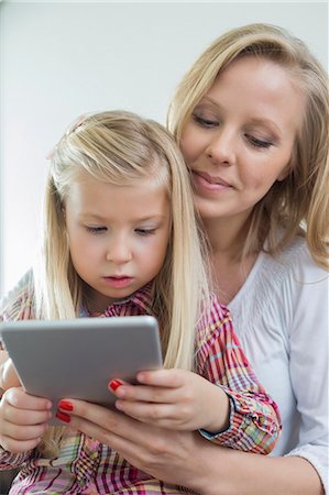 Loving woman with daughter using digital tablet at home Photographie de stock - Premium Libres de Droits, Code: 693-07542233