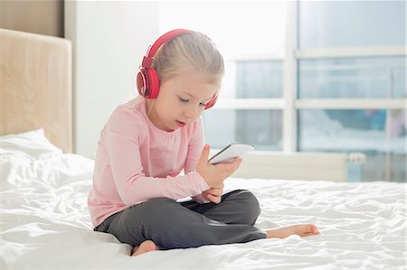 Full length of girl listening music on headphones in bedroom Stock Photo - Premium Royalty-Free, Code: 693-07542245