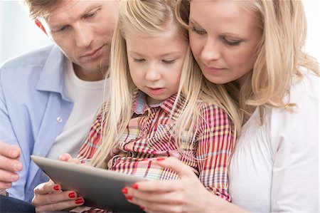 Mid adult parents using tablet PC with daughter at home Stock Photo - Premium Royalty-Free, Code: 693-07542251