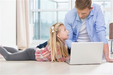 Father and daughter using laptop on floor in living room Stock Photo - Premium Royalty-Free, Code: 693-07542252