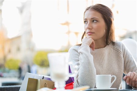 Young woman looking away while sitting at sidewalk cafe Stock Photo - Premium Royalty-Free, Code: 693-07542277