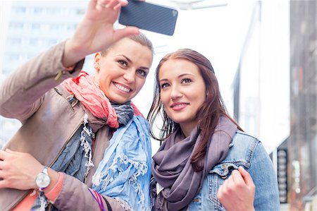 people communicating technology - Women in jackets taking self portrait through mobile phone Stock Photo - Premium Royalty-Free, Code: 693-07542324