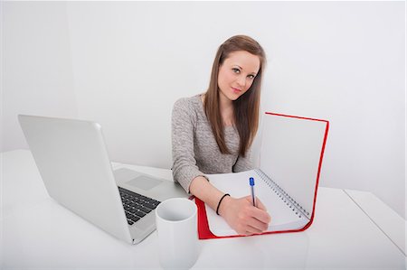 desk with wall - Portrait of beautiful businesswoman writing in book at office desk Stock Photo - Premium Royalty-Free, Code: 693-07542331