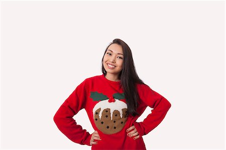 Portrait of woman in Christmas sweater standing with hands on hips over gray background Stock Photo - Premium Royalty-Free, Code: 693-07542365