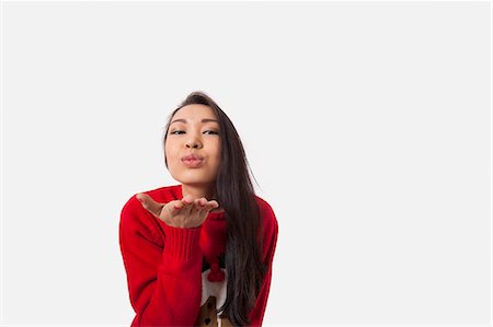 simsearch:693-06379982,k - Portrait of woman in Christmas sweater blowing kiss over gray background Stock Photo - Premium Royalty-Free, Code: 693-07542366