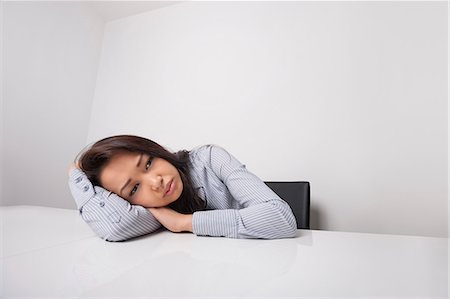 Tired businesswoman leaning at office desk Foto de stock - Sin royalties Premium, Código: 693-07542362