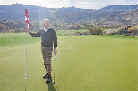 Full length portrait of happy senior male golfer holding flag and putter at golf course Photographie de stock - Premium Libres de Droits, Code: 693-07672534