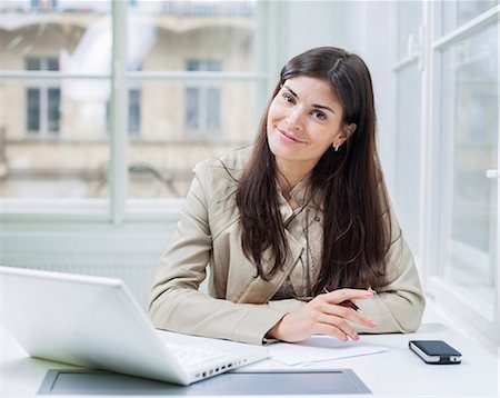 Portrait of confident businesswoman with laptop sitting at office desk Photographie de stock - Premium Libres de Droits, Code: 693-07672561