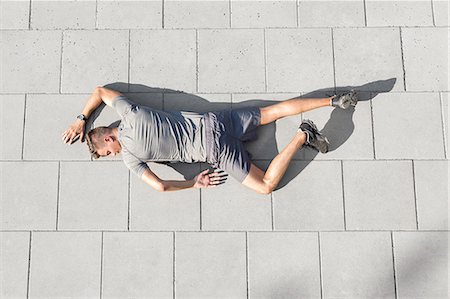 person lying back above view - High angle view of tired sporty man lying on tiled sidewalk Stock Photo - Premium Royalty-Free, Code: 693-07672609