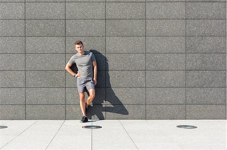sidewalk - Full length portrait of confident sporty man leaning on tiled wall Stock Photo - Premium Royalty-Free, Code: 693-07672610