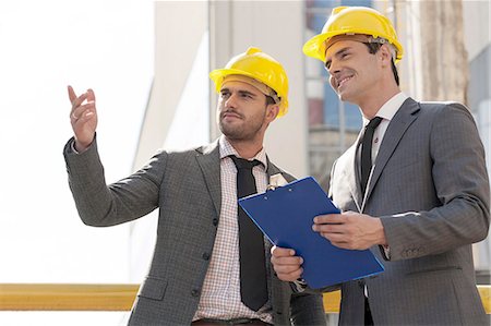 Young male architects with clipboard discussing at construction site Stockbilder - Premium RF Lizenzfrei, Bildnummer: 693-07672639