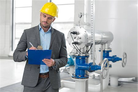 Young male manager writing on clipboard in industry Foto de stock - Sin royalties Premium, Código: 693-07672632