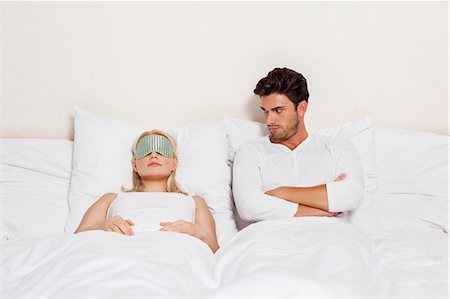 Angry young man looking at woman sleeping in bed Photographie de stock - Premium Libres de Droits, Code: 693-07672669