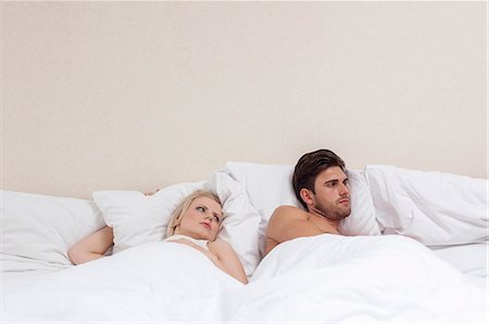 Angry young man ignoring woman in bed Stock Photo - Premium Royalty-Free, Code: 693-07672714