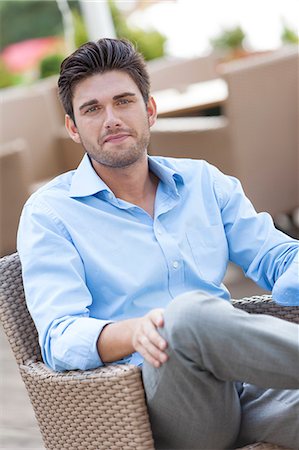Portrait of young man sitting on chair at outdoors cafe Stock Photo - Premium Royalty-Free, Code: 693-07672742