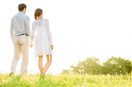 Rear view of young couple holding hands in park against clear sky Stock Photo - Premium Royalty-Free, Code: 693-07672753