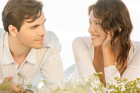 simsearch:693-07672803,k - Loving couple looking at each other while lying against clear sky Stock Photo - Premium Royalty-Free, Code: 693-07672770