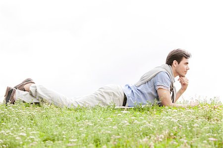 simsearch:693-07672803,k - Full length of thoughtful young man lying on grass against clear sky Stock Photo - Premium Royalty-Free, Code: 693-07672781