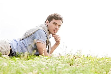 simsearch:693-07672803,k - Portrait of young man lying on grass against clear sky Stock Photo - Premium Royalty-Free, Code: 693-07672782