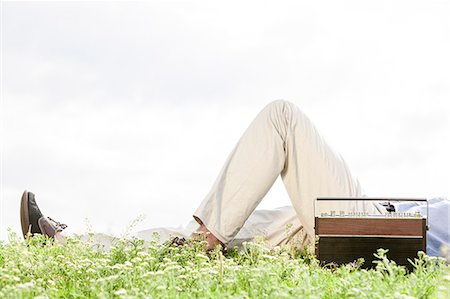 simsearch:693-07672803,k - Low section of man lying by vintage radio on grass against clear sky Stock Photo - Premium Royalty-Free, Code: 693-07672792