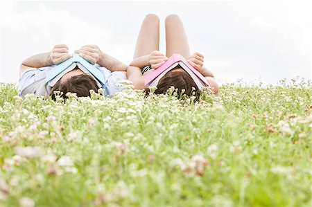 flower relax - Relaxed young couple covering faces with books while lying on grass Stock Photo - Premium Royalty-Free, Code: 693-07672807