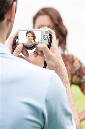 person holding a camera - Young man photographing woman through digital camera in park Stock Photo - Premium Royalty-Free, Code: 693-07672817