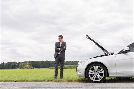 Young businessman standing arms crossed by broken down car at countryside Photographie de stock - Premium Libres de Droits, Code: 693-07672835