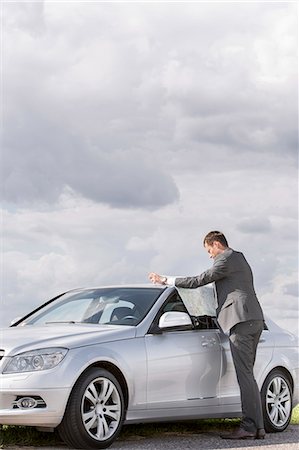 Full length side view of businessman reading map by car at countryside Foto de stock - Sin royalties Premium, Código: 693-07672849