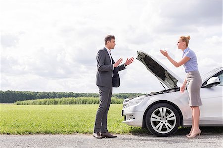 displeased - Full length side view of business couple arguing over broken car at countryside Stock Photo - Premium Royalty-Free, Code: 693-07672842