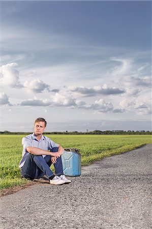 simsearch:693-07672829,k - Full length of young man with empty petrol can sitting by country road Stock Photo - Premium Royalty-Free, Code: 693-07672864