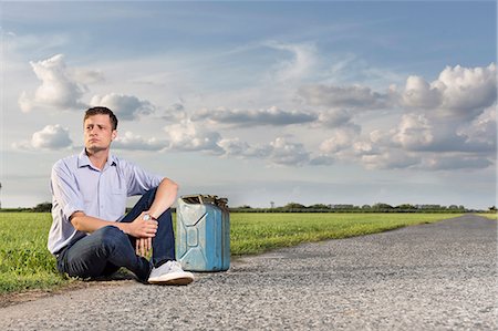 simsearch:693-07672829,k - Full length of young man with empty gas can sitting by country road Stock Photo - Premium Royalty-Free, Code: 693-07672863