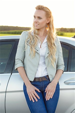 simsearch:693-03309039,k - Beautiful young woman looking away while standing by car at countryside Fotografie stock - Premium Royalty-Free, Codice: 693-07672872