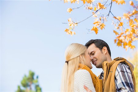 Low angle view of couple kissing against clear sky during autumn Stock Photo - Premium Royalty-Free, Code: 693-07672899