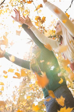 sweater winter - Couple with arms raised enjoying falling autumn leaves in park Stock Photo - Premium Royalty-Free, Code: 693-07672917