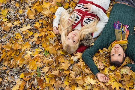 seasons photographs - High angle portrait of young couple lying on autumn leaves at park Stock Photo - Premium Royalty-Free, Code: 693-07672913