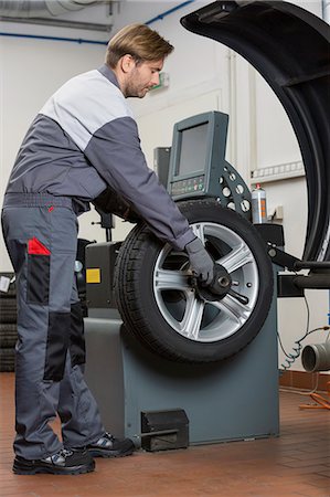 Side view of male mechanic repairing car's wheel in workshop Foto de stock - Sin royalties Premium, Código: 693-07672924