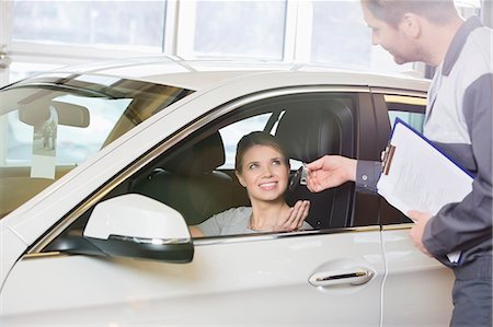 simsearch:693-07672920,k - Smiling female customer receiving car key from mechanic in workshop Photographie de stock - Premium Libres de Droits, Code: 693-07672934