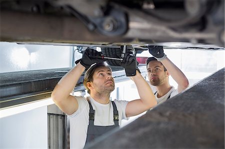 simsearch:693-07672922,k - Maintenance engineers repairing car in workshop Foto de stock - Sin royalties Premium, Código: 693-07672947