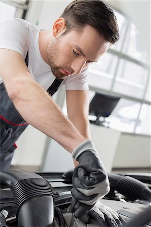 Young maintenance engineer repairing car in automobile store Foto de stock - Sin royalties Premium, Código: 693-07672958