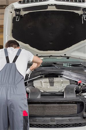 Rear view of male engineer repairing car in automobile repair shop Foto de stock - Sin royalties Premium, Código: 693-07672959