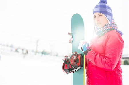 Beautiful young woman in warm clothing holding snowboard during winter Foto de stock - Sin royalties Premium, Código: 693-07673075