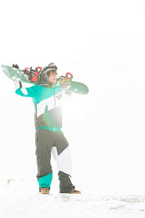 snow sports - Full length of young man carrying snowboard in snow Stock Photo - Premium Royalty-Free, Code: 693-07673093